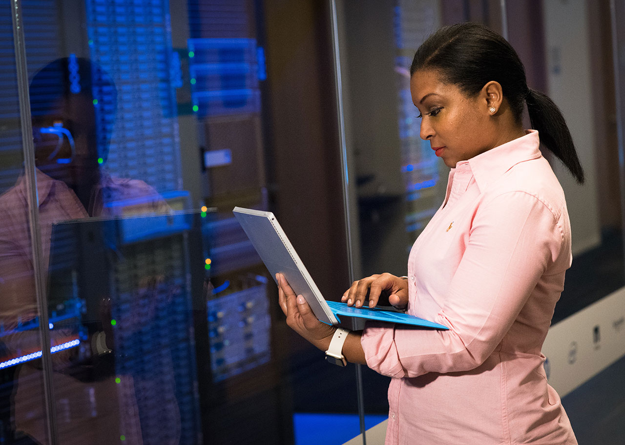 woman working a laptop in front of a server